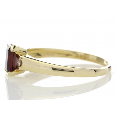 67 - An emerald cut garnet gemstone sits between two round brilliant cut diamonds set into the shoulders ... 