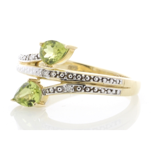 68 - Two pear shaped peridot are set alongside six diamonds on the band and shoulders of this split top 9... 