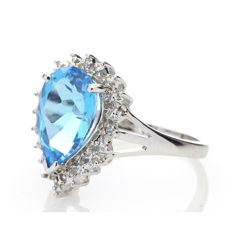 76 - A stunning pear shaped Blue Topaz 3.23 carats sits surrounded by a halo set with four single cut dia... 