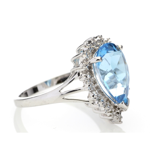 76 - A stunning pear shaped Blue Topaz 3.23 carats sits surrounded by a halo set with four single cut dia... 