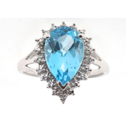 76 - A stunning pear shaped Blue Topaz 3.23 carats sits surrounded by a halo set with four single cut dia... 