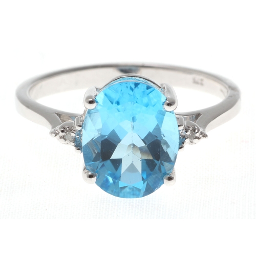 80 - An oval cut Blue Topaz 2.10 carats sits between two round brilliant cut diamonds in this gorgeous 9c... 