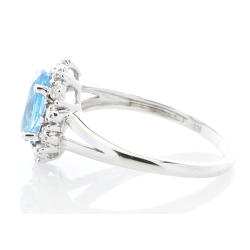 84 - An oval blue topaz is surrounded by a halo or diamonds on this stunning 9ct white gold split shank d... 