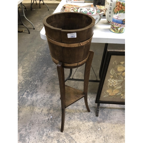 283 - A CIRCULAR OAK BARREL JARDINIERE WITH COPPER BANDED SUPPORTS 91cm HEIGHT