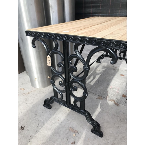 10 - A SLATTED WOODEN GARDEN TABLE WITH CAST IRON ENDS - 110 CM X 70 CM