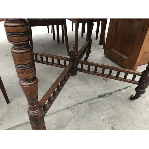 932 - AN OCTAGONAL OAK DINING TABLE ON TURNED SUPPORTS WITH LOWER GALLERIED STRETCHER RAIL