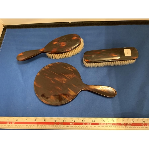 57 - A TORTOISHELL EFFECT THREE PIECE DRESSING TABLE SET COMPRSING OF A  MIRROR AND TWO BRUSHES