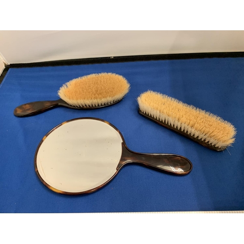 57 - A TORTOISHELL EFFECT THREE PIECE DRESSING TABLE SET COMPRSING OF A  MIRROR AND TWO BRUSHES