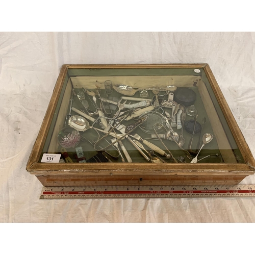 131 - A WOODEN FRAMED GLASS TOPPED JEWELLERY DISPLAY CABINET (A/F) WITH A LARGE QUANTITY OF EPNS