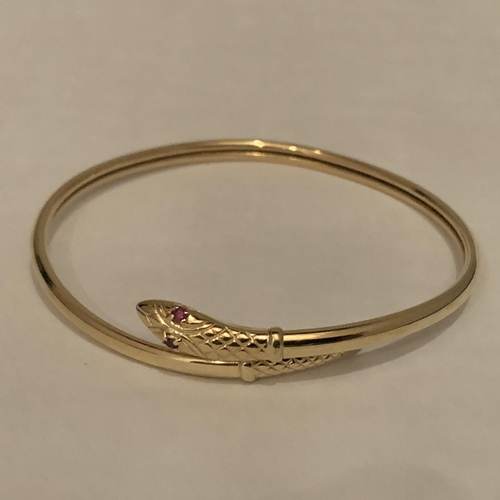 616 - A 9 CARAT GOLD SNAKE BANGLE WITH RED STONE SET EYES. TOTAL GROSS WEIGHT 8.7 GRAMS