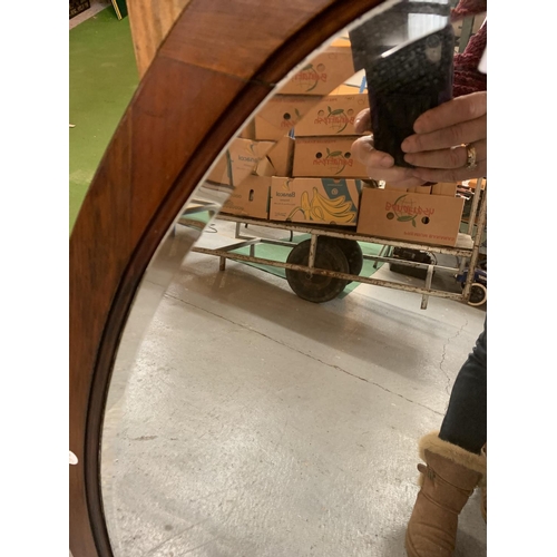 713 - EARLY 20TH CENTURY OVAL MAHOGANY FRAMED WALL MIRROR WITH BEVELLED GLASS, 55 X 98 CM