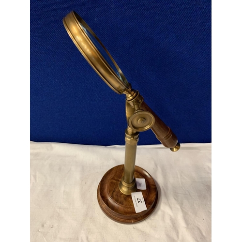 37 - A VINTAGE BRASS MAGNIFTING GLASS ON A WOOD AND BRASS STAND