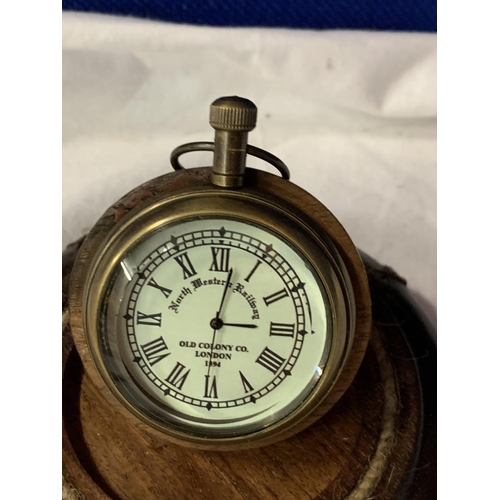 64 - A BRASS POCKET WATCH ON A LEATHER BASE WITH A GLASS DOME