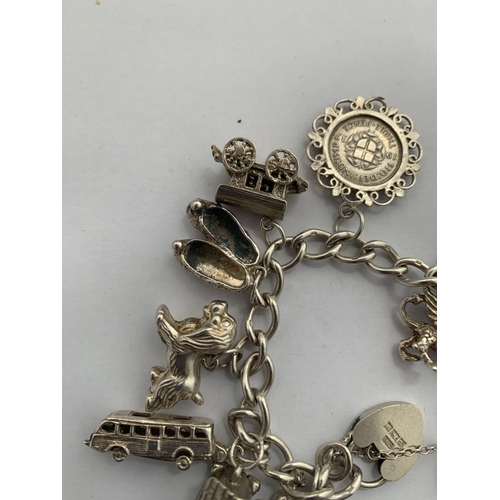 606 - A HALLMARKED SILVER CHARM BRACELET WITH TWELVE CHARMS