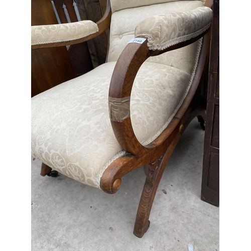 2140 - A 19TH CENTURY OAK FIRESIDE CHAIR ON X FRAME WITH SWEPT BACK AND BRASS CASTERS