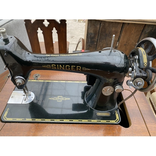 2141 - A VINTAGE SINGER SEWING MACHINE IN A WALNUT CABINET