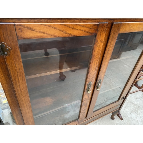 1827A - AN EARLY 20TH CENTURY OAK TWO DOOR BOOKCASE ON CABRIOLE LEGS