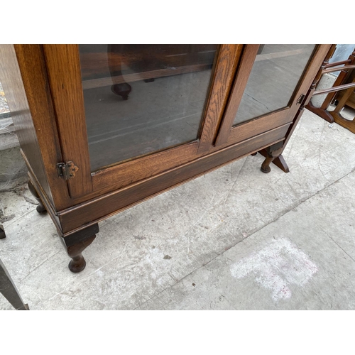 1827A - AN EARLY 20TH CENTURY OAK TWO DOOR BOOKCASE ON CABRIOLE LEGS