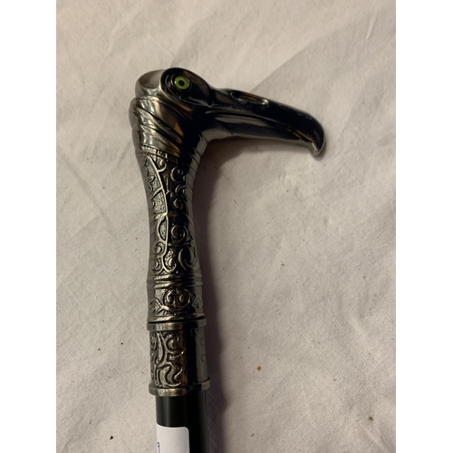 32 - A WALKING STICK WITH A WHITE METAL EAGLES HEAD WITH GREEN GLASS EYES