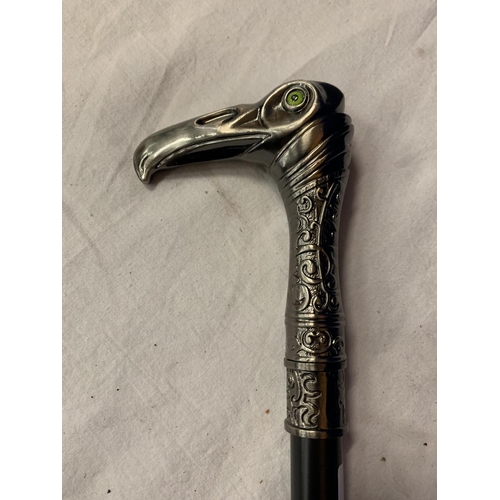 32 - A WALKING STICK WITH A WHITE METAL EAGLES HEAD WITH GREEN GLASS EYES