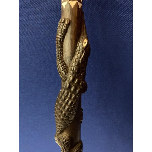 40 - AN INTRICATELY CARVED WOODEN STICK WITH MOTHER OF PEARL STYLE DETAIL AND CROCODILE AND SNAKE DESIGN