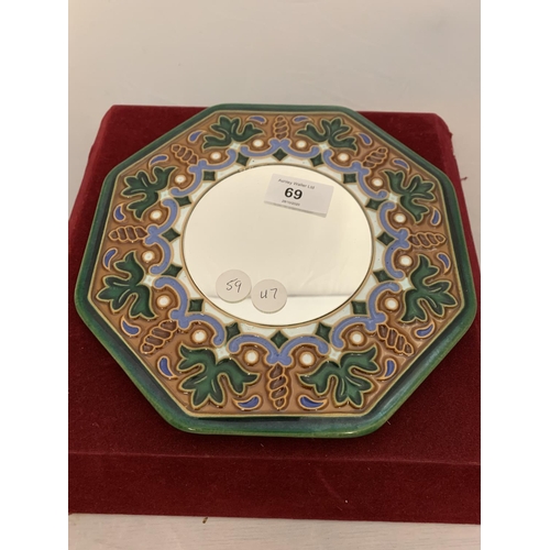 69 - A SMALL CIRCULAR MIRROR WITH A DECORATED CERAMIC SURROUND