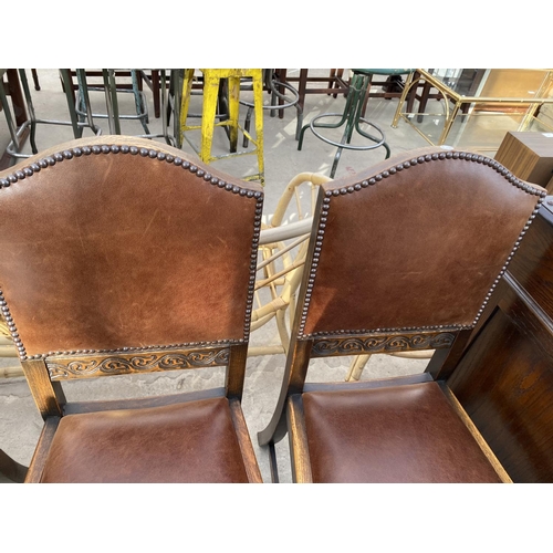 1933 - A SET OF FOUR EARLY 20TH CENTURY OAK DINING CHAIRS WITH LEATHER SEATS AND BACKS WITH STUDDED DECORAT... 