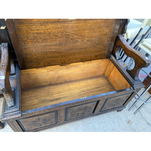 2137 - AN EARLY 20TH CENTSURY OAK MONKS BENCH WITH CARVED THREE PANEL FRONT, 43