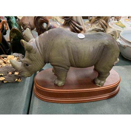 87 - AN ASSORTMENT OF EIGHT ANIMAL FIGURES TO INCLUDE A LARGE RHINO ON A WOODEN PLINTH ETC