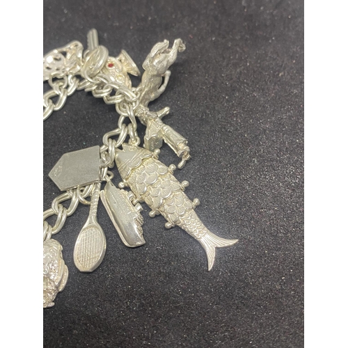 505 - A SILVER CHARM BRACELET WITH SIXTEEN VARIOUS CHARMS TO INCLUDE A FISH, BIRD CAGE, BOAT ETC