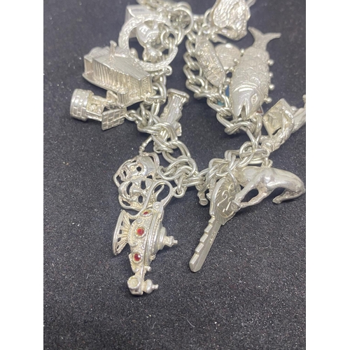 505 - A SILVER CHARM BRACELET WITH SIXTEEN VARIOUS CHARMS TO INCLUDE A FISH, BIRD CAGE, BOAT ETC