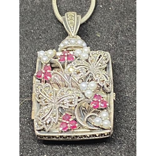 522 - A SILVER NECKLACE WITH AN ORNATE LOCKET WOTH RED STONES AND CLEAR STONE CHIPS IN A DELICATE FLORAL D... 