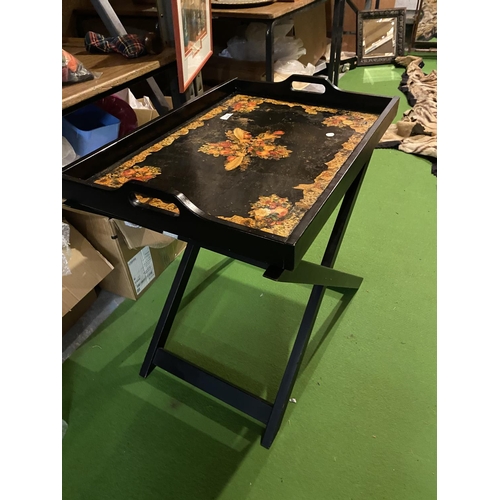 658 - A LARGE BLACK LAQUERED BUTLER'S TRAY WITH FLORAL DECORATION ON A FOLD OUT STAND ( 50 CM X 69 CM)