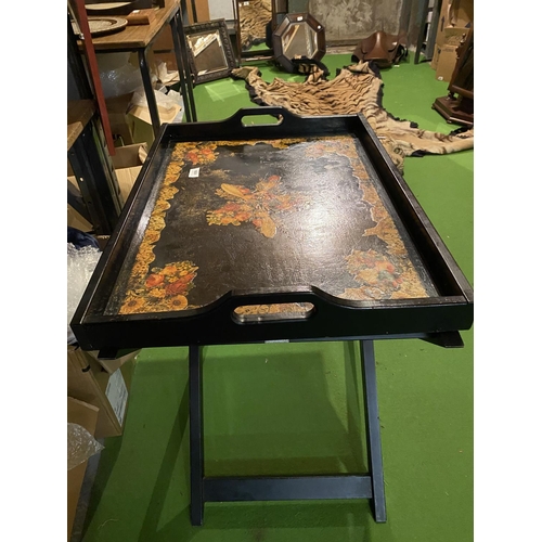 658 - A LARGE BLACK LAQUERED BUTLER'S TRAY WITH FLORAL DECORATION ON A FOLD OUT STAND ( 50 CM X 69 CM)