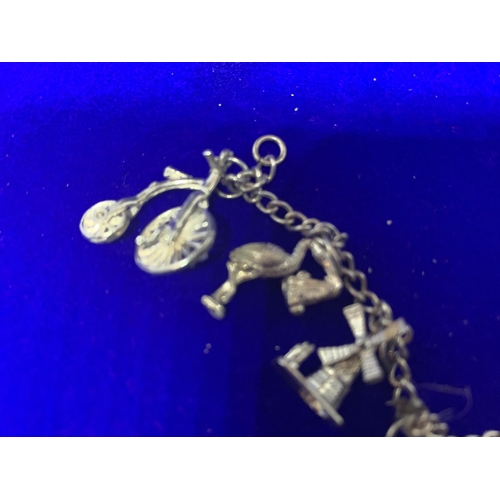 522 - A SILVER CHARM BRACELET MARKED STERLING WITH EIGHT VARIOUS CHARMS IN A PRESENTATION BOX