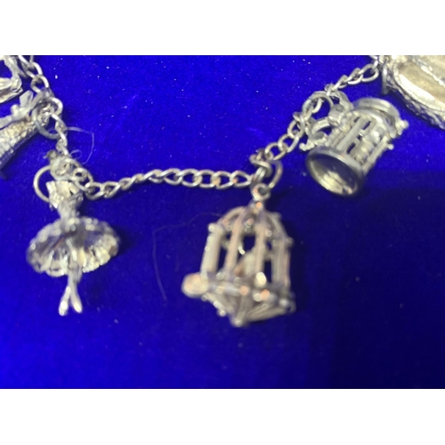 522 - A SILVER CHARM BRACELET MARKED STERLING WITH EIGHT VARIOUS CHARMS IN A PRESENTATION BOX