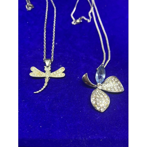 579 - FOUR SILVER NECKLACES WITH PENDANTS TO INCLUDE A FLOWER, DRAGON FLY, LOCKET AND CROSS MARKED 925 /ST... 