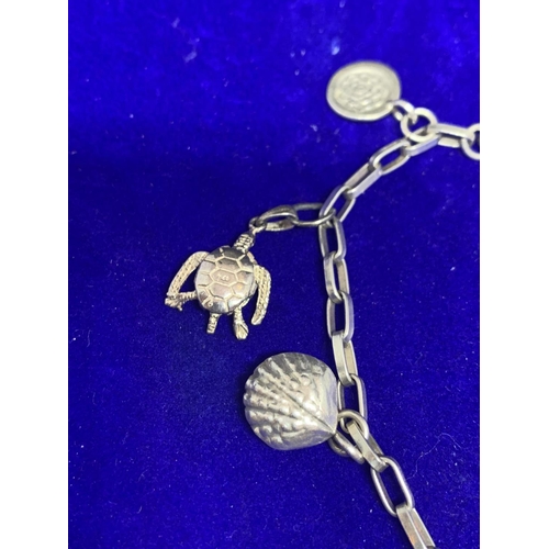 633 - A SILVER CHARM BRACELET WITH NINE CHARMS TO INCLUDE CLOGS, FEATHERS, TURTLE, FISH, SHELL ETC