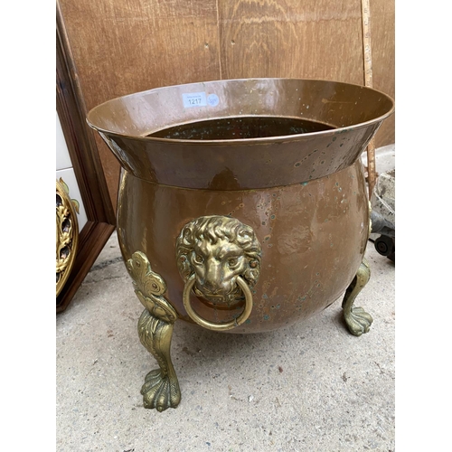 1217 - A BRASS AND COPPER CAULDRON WITH DECORATIVE CLAW FEET AND LION HEAD HANDLES