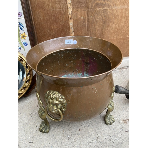 1217 - A BRASS AND COPPER CAULDRON WITH DECORATIVE CLAW FEET AND LION HEAD HANDLES