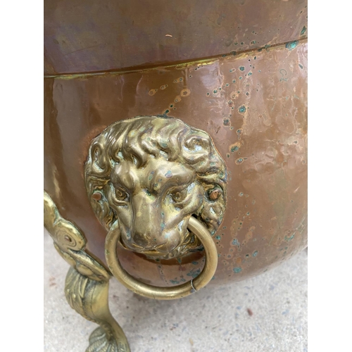 1217 - A BRASS AND COPPER CAULDRON WITH DECORATIVE CLAW FEET AND LION HEAD HANDLES