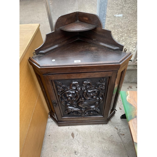 1904 - A LATE VICTORIAN OAK CORNER CUPBOARD WITH HEAVILY CARVED SINGLE DOOR AND SHAPED INTERIOR SHELF, 26