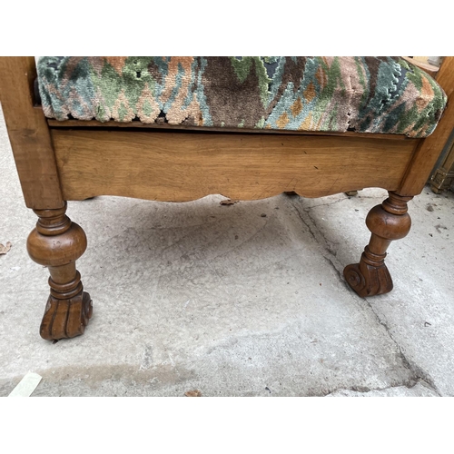 1908 - AN EARLY 20TH CENTURY WALNUT FRAMED LOW ELBOW CHAIR ON TURNED BULBOUS LEGS AND SCROLL FEET