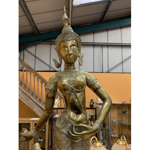 34 - A LARGE BRASS STATUE OF A ORIENTAL TEMPLE DANCER ON A WOODEN PLINTH - HEIGHT 79 CM