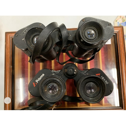 140 - A SMALL GLAZED DISPLAY CABINET 38CMS X 27CMS AND TWO PAIRS OF BINOCULARS TO INCLUDE AJAX AND PRISMA