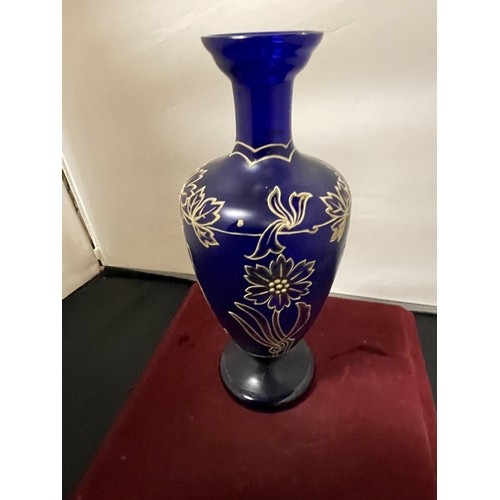 360 - A BLUE GLASS URN WITH GOLD RELIEF FLOWER PATTERN (HEIGHT 26CM)