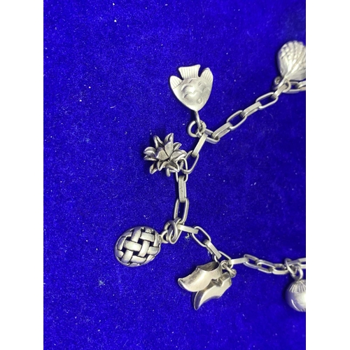 633 - A SILVER CHARM BRACELET WITH NINE CHARMS TO INCLUDE CLOGS, FEATHERS, TURTLE, FISH, SHELL ETC