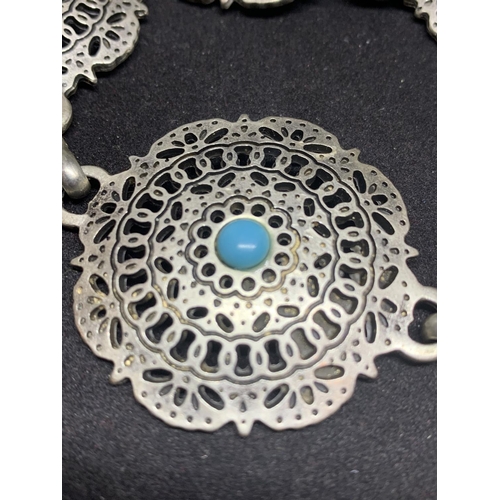 510 - A WHITE METAL BELT WITH ORNATE DISCS AND TURQUOISE STONES IN A NAVAJO STYLE