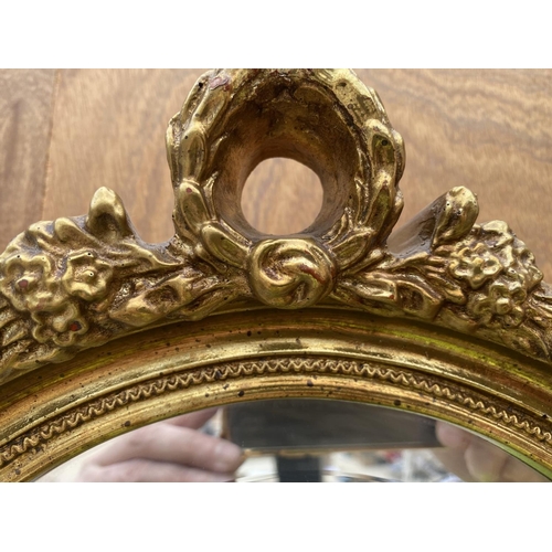 1357 - A DECORATIVE OVAL GILT FRAMED MIRROR