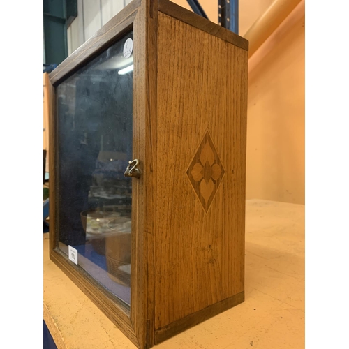 163 - AN INLAID OAK GLASS CABINET TO INCLUDE TWO TREEN LIDDED BOWLS